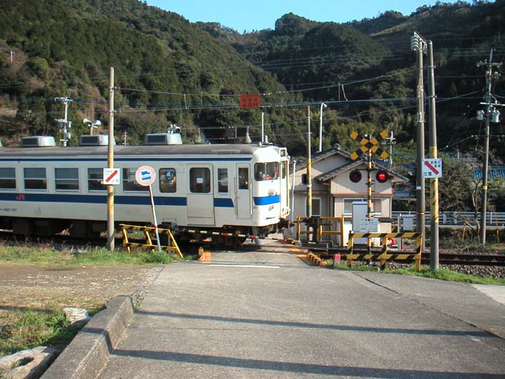 鹿児島本線の踏切を通過する普通列車